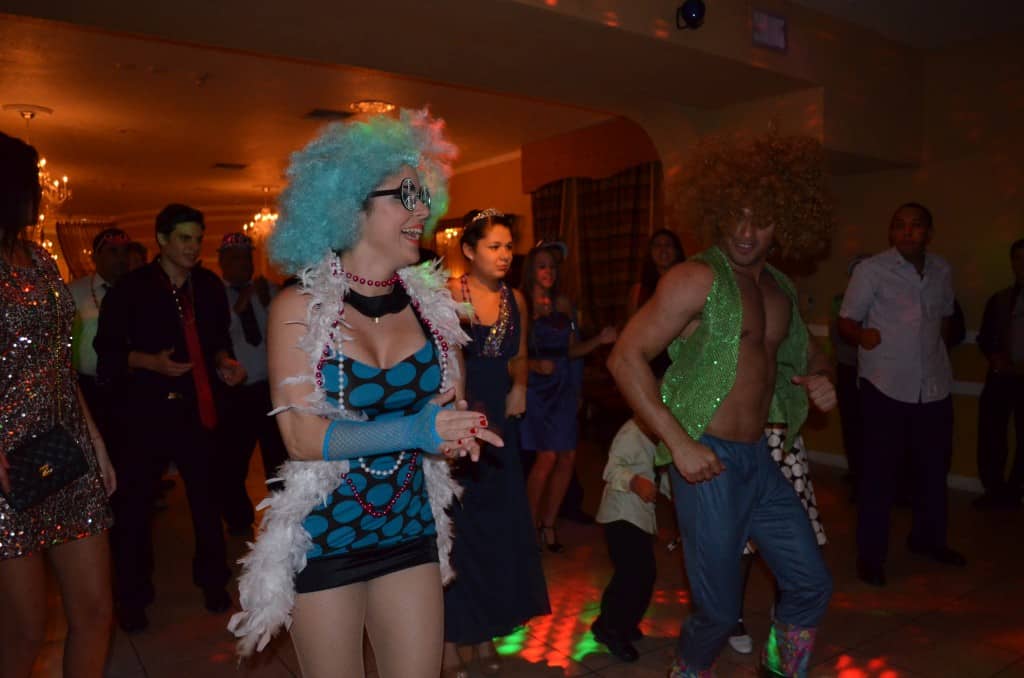 girl in dot dress and blue afro and man with green glitter vest with orange afro