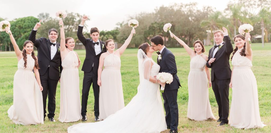 A newly wedding couple kissing with their friends celebrating next to them