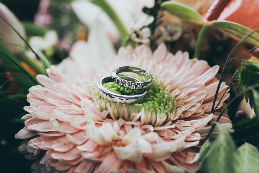 Two wedding rings sitting on a flower